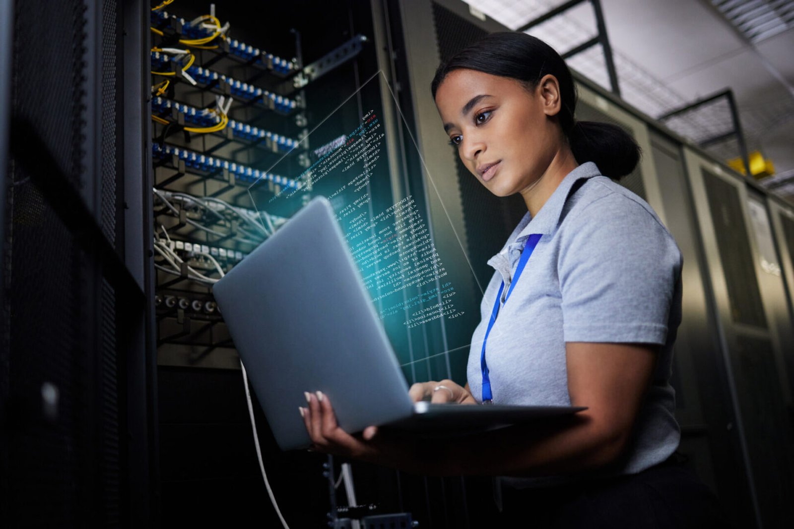 Woman working on laptop in server room.