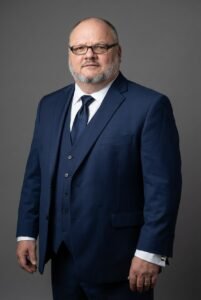 Man in blue suit with glasses.