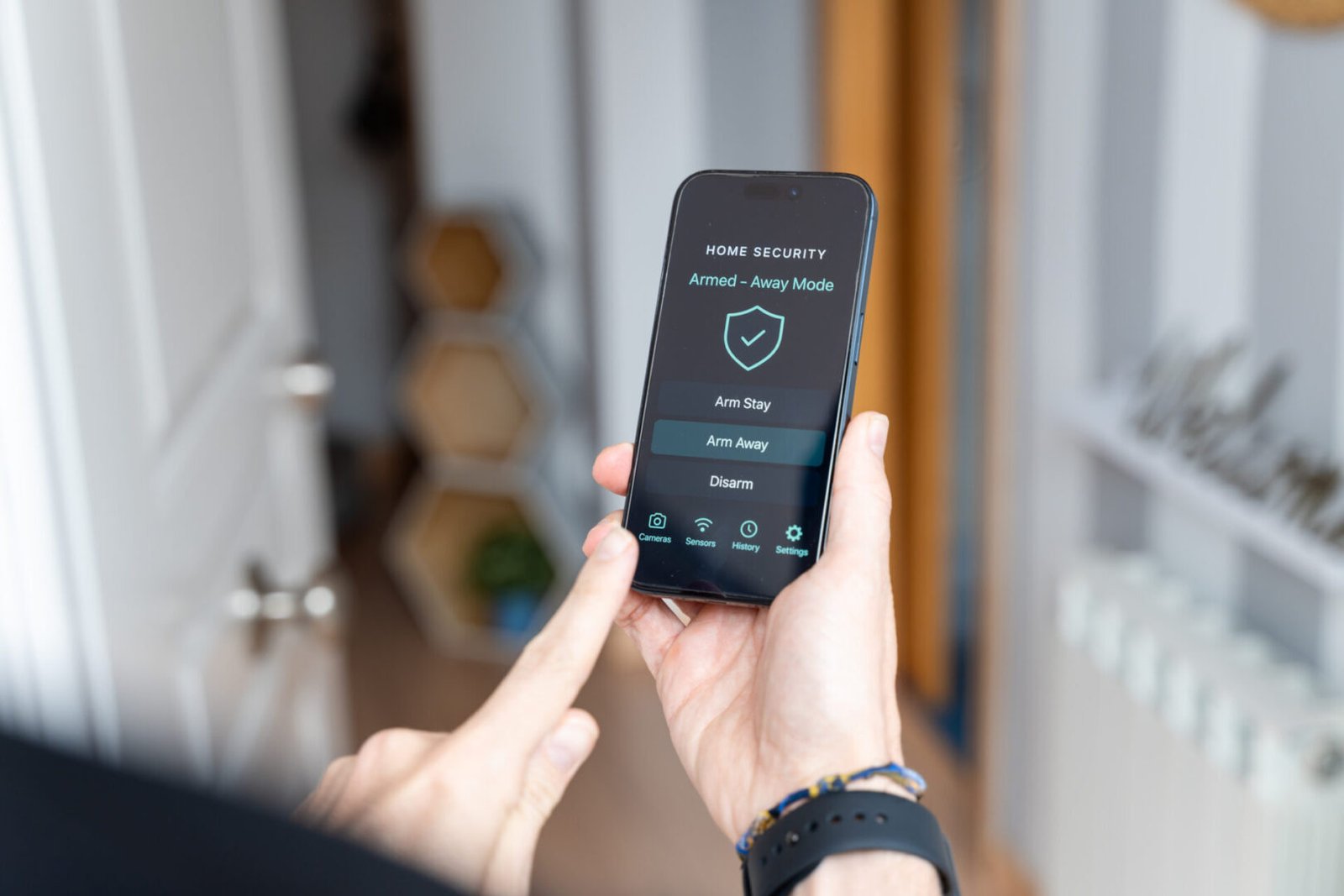 Person using home security app on smartphone.